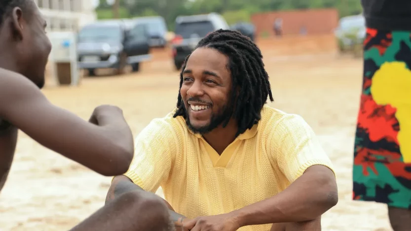 Kendrick Lamar is gearing up for the release of his highly-anticipated new album dubbed Mr. Morale & The Big Steepers. In this regard, he has been in Ghana, and a video of him enjoying a soccer game with people in Ghana has surfaced. While it is not the sort of the great games you would wager on the bettors.com.gh site, it got massive attention globally. Before that, another video of the Compton rapper hanging out in Ghana had already gone viral before his LP’s release. Sunday, May 15th, was when Mr. Morale stepped out to enjoy a soccer match with some Ghanaians. The natives appreciated the gesture and shared the video of the game online. In the clip, Lamar is seen waiting as his teammates fight for possession before he makes a goal attempt. In another part of the footage, K Dot is seen posing for a group photo with others who took part in the game. Lamar wore a yellow t-shirt and red shorts, and you can see behind the players in the videos a wall covered with murals. One of the murals was of iconic rapper Tupac Shakur whose voice features on Lamar’s album To Pimp Butterfly. It is not clear how long Lamar has been in Africa, but according to rumors, the rapper was visiting Ghana to host an exclusive listening party before the release of his album. Others claim that he is filming a documentary in the country. Apple Music claims that Kendrick Lamar’s fifth solo studio album is smashing records on the platform. In a tweet, the streaming platform wrote that Lemar’s new album recorded the most first-day streams for an album released in 2022. Lemar will also be going for a world tour surrounding his new LP. The tour, dubbed The Big Steppers Tour, will span 65 dates and kick off on July 19th in Oklahoma City. It will then close in Australia in December. Some reports claim the multi-award-winning rapper has been in Ghana for about a week and has visited several locations across the City. Several videos have shown the rapper having a great time as he gets to know the people and their culture. For example, he is said to have visited a skate park. Another video that has gone viral is of Lamar playing video games with young Ghanaian kids. He is captured wholly focused as he enjoyed the video games. It is understood the game they were enjoying was the popular soccer video game – EA Sports FIFA, at a local game center with a group of young children.